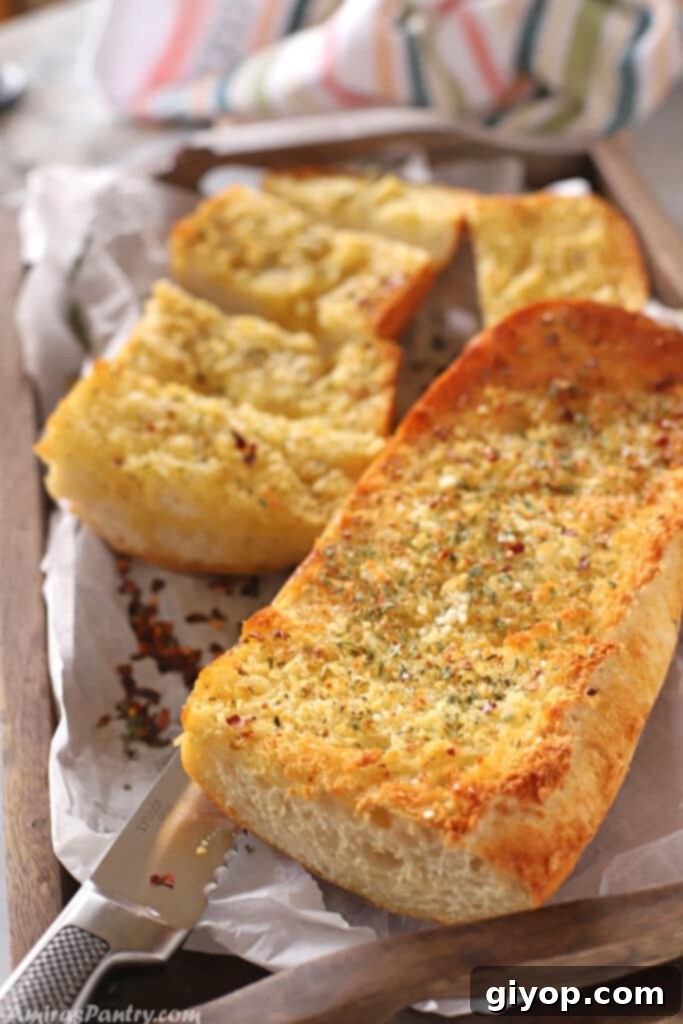 Crusty garlic bread on a tray with a knife.