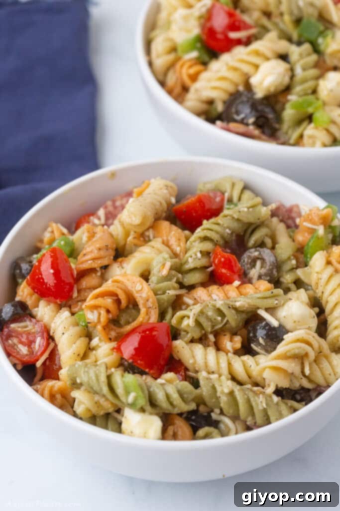 A close-up shot of a white bowl brimming with a vibrant Italian pasta salad, featuring colorful vegetables and perfectly cooked pasta.