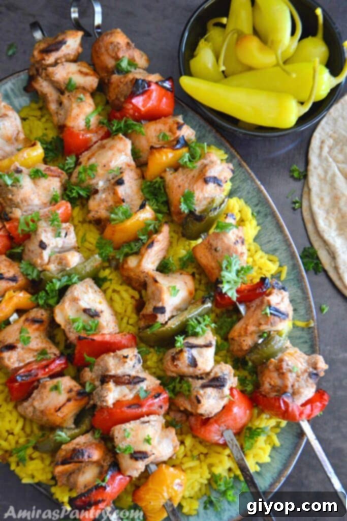 Succulent Middle Eastern Grilled Chicken Kabob skewers, perfectly charred and tender, served invitingly over a bed of fragrant yellow rice.