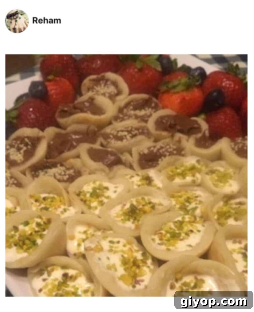 A close up of food, with stuffed Qatayef made by a fan, beautifully arranged with pistachios.