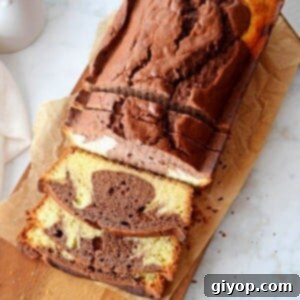 An overhead view of a sliced marble pound cake placed on a wooden cutting board, showcasing its beautiful swirls.