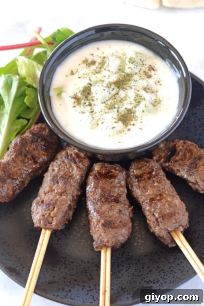 Platter of juicy Kofta Kebabs on skewers, served with a creamy dip and fresh garnishes.