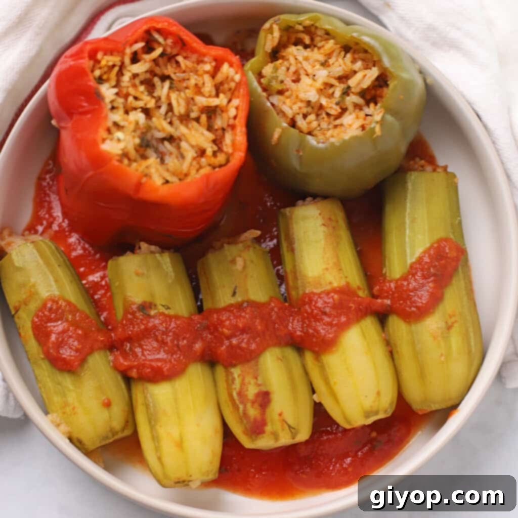 A serving plate with stuffed zucchini and bell peppers with tomato sauce.