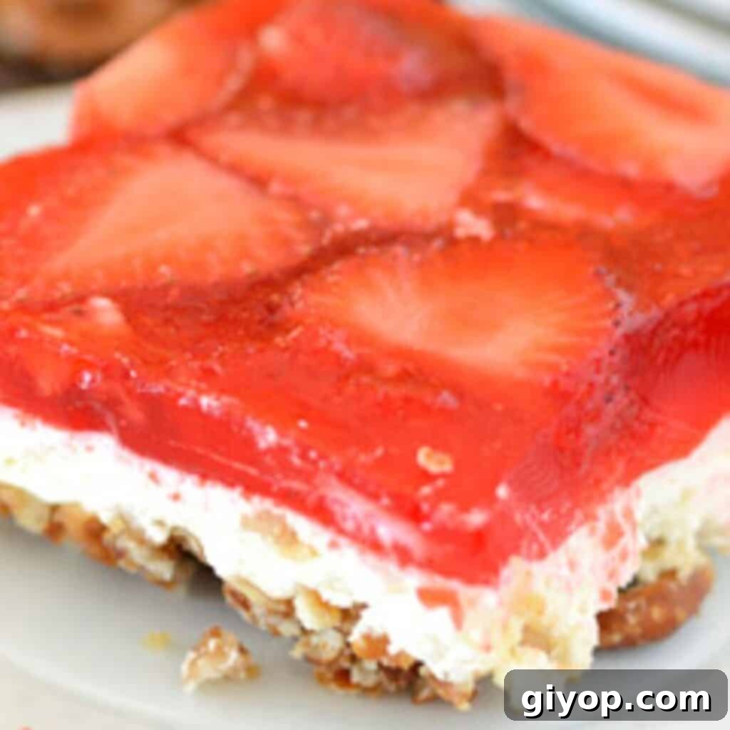 A close up image for a piece of strawberry pretzel salad on a white plate.