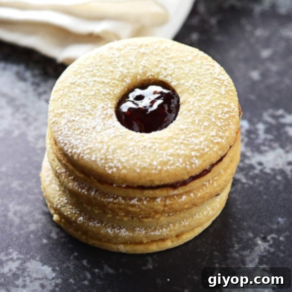 A stack of Linzer cookies on a dark surface.