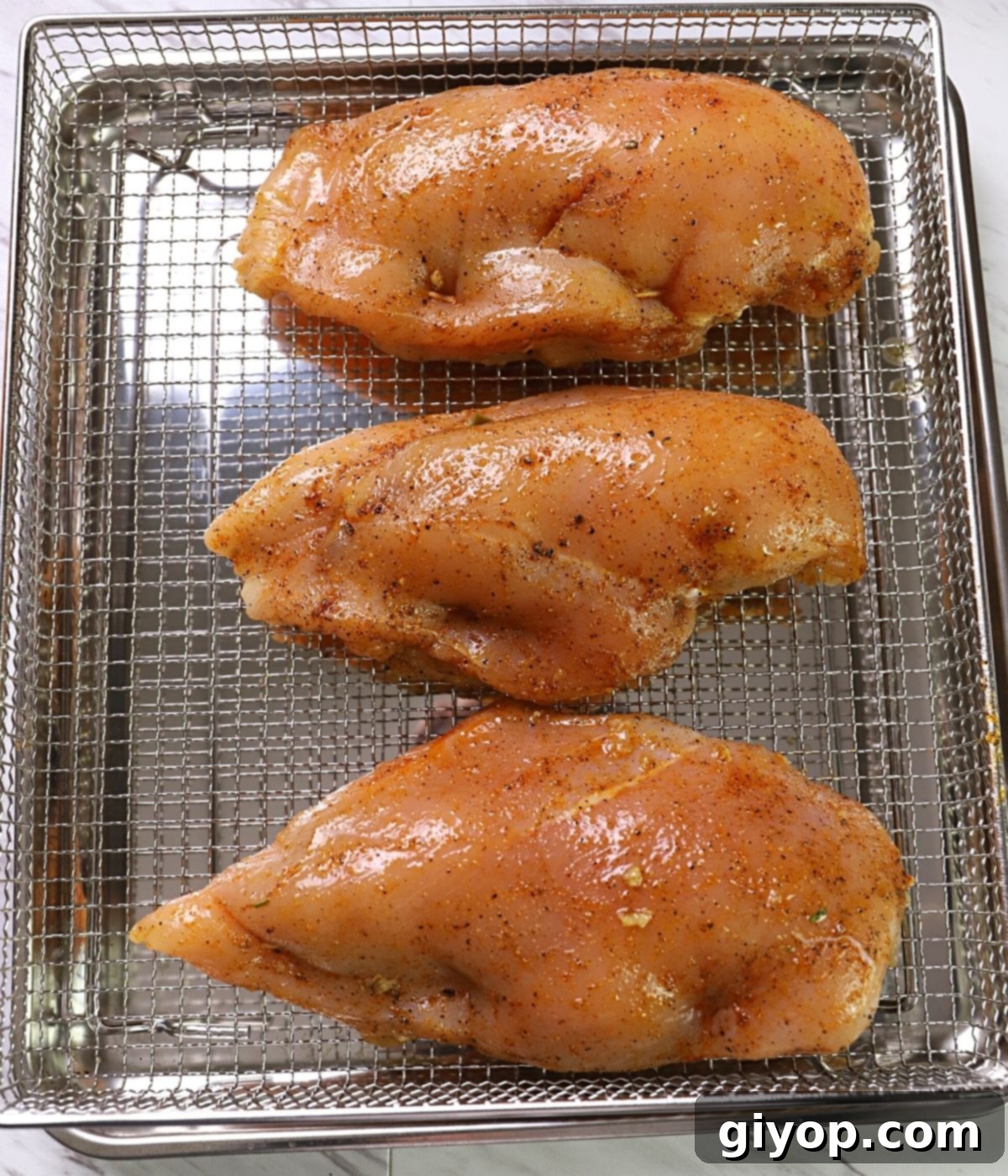 Air fryer basket with three stuffed chicken breasts.