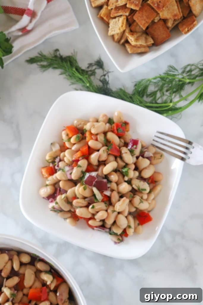 Fresh and vibrant Mediterranean white bean salad served on a white plate, garnished with dill, ready as a light lunch or dinner side.