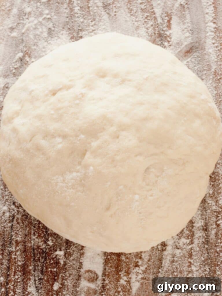 Freshly prepared homemade pizza dough resting on a rustic wooden surface, ready to be topped for a fun Friday night pizza.