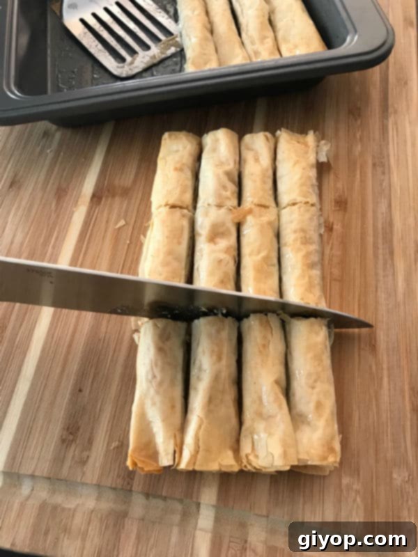 Golden, crispy Baklava rolls elegantly cut on a wooden board, showcasing layers of pastry and nuts, perfect for a sweet treat.