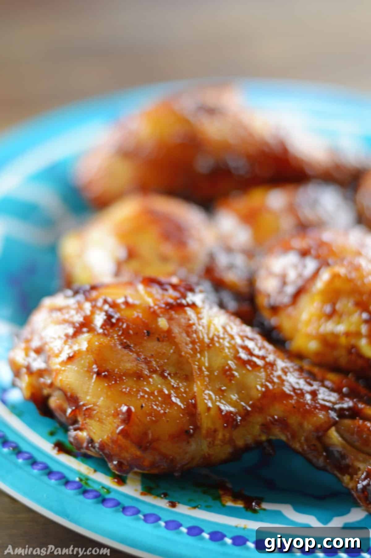 Perfectly glazed BBQ drumsticks on a blue plate, resting on a rustic wooden countertop, ready to be served.