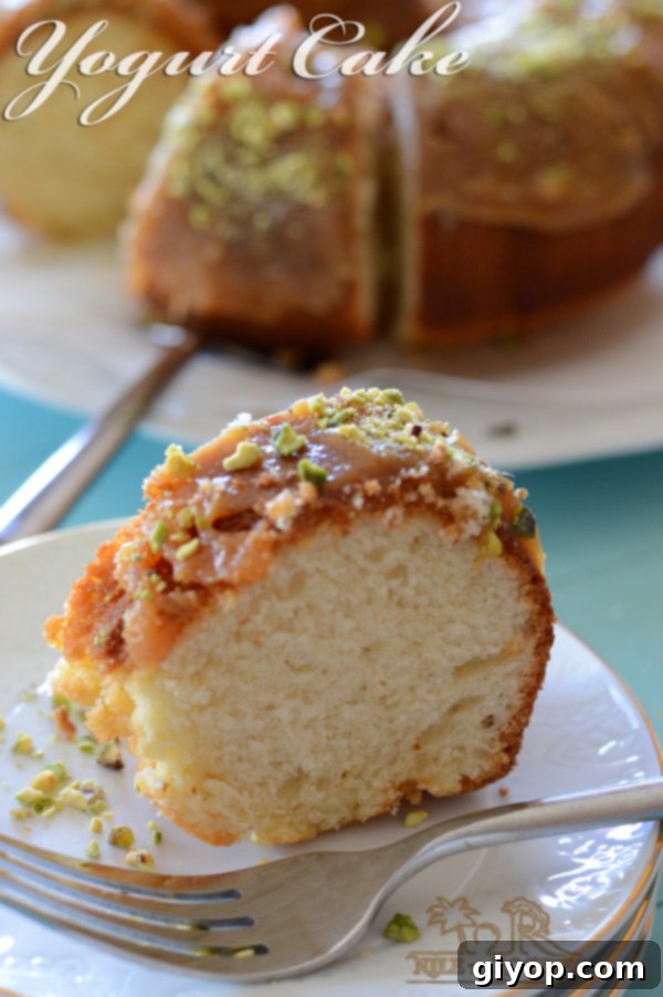 A close-up of a slice of moist yogurt cake topped with toffee sauce and crushed nuts