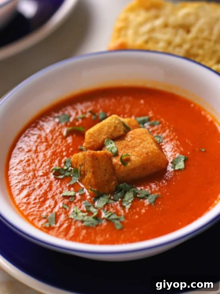 Creamy tomato basil soup in a white bowl with a blue rim, garnished with fresh chopped basil leaves.