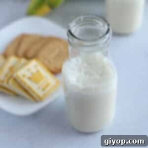 A bottle of banana milk with cookies and bananas on the background.