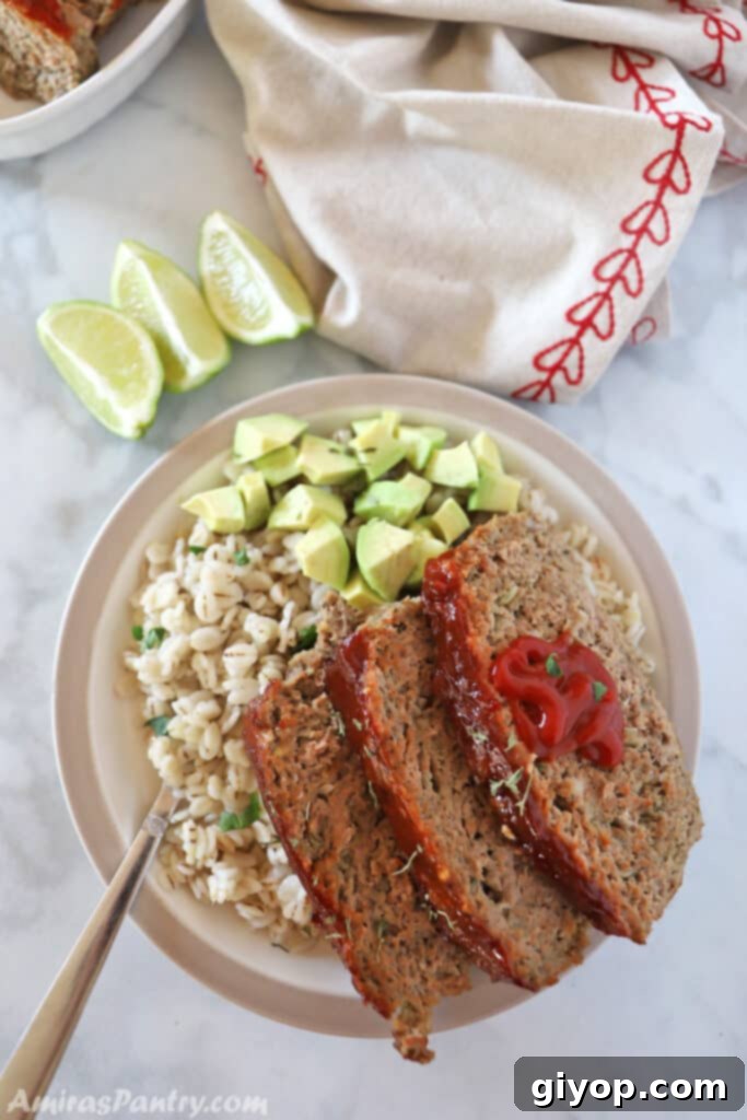 Slices of moist Turkey Meatloaf, garnished with diced avocados, on a plate, indicating a healthy and flavorful meal.