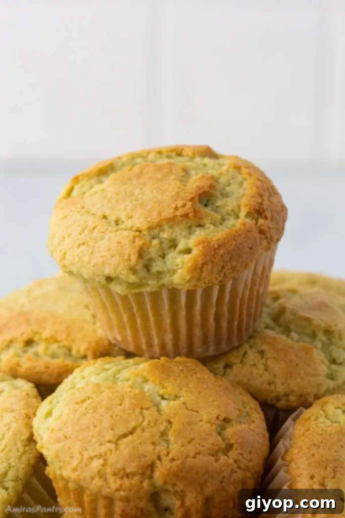 A beautiful stack of vibrant green Pistachio Muffins on a white background, highlighting their moist texture and nutty appeal.