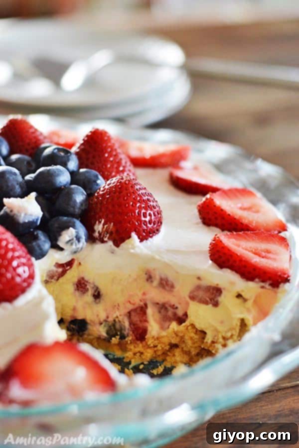 Close-up of a serving of No-Bake Berry Golden Oreo Dessert, showing a cross-section of the layers and the vibrant colors of the berries.