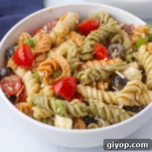 A white bowl of pasta salad on a marble surface.