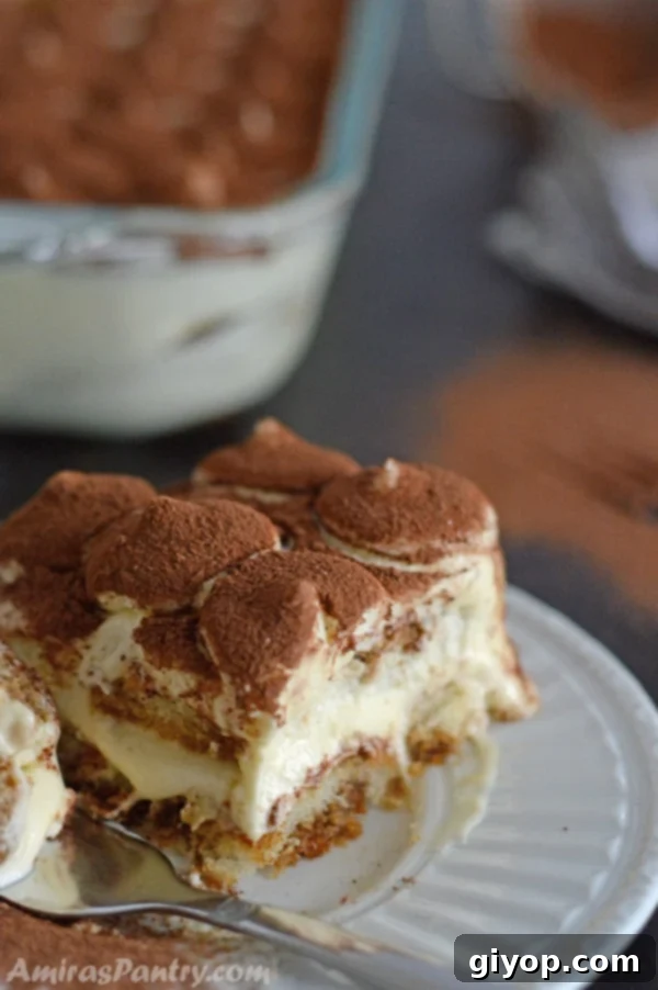An elegantly presented tiramisu, layered with coffee-soaked ladyfingers, rich mascarpone cream, and dusted with cocoa powder, ready to be served.