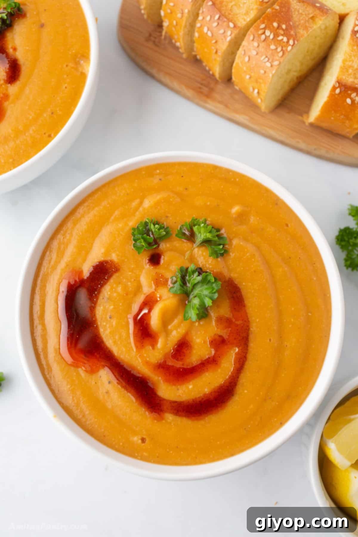 An overhead shot of white soup bowls with bread sliced on the side.