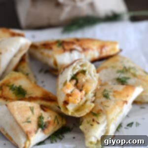 Baked samosa on a white plate with one cut to show shrimp filling.