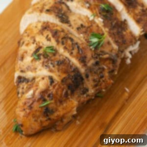 A close up image on a grilled chicken breast on a wooden cutting board.