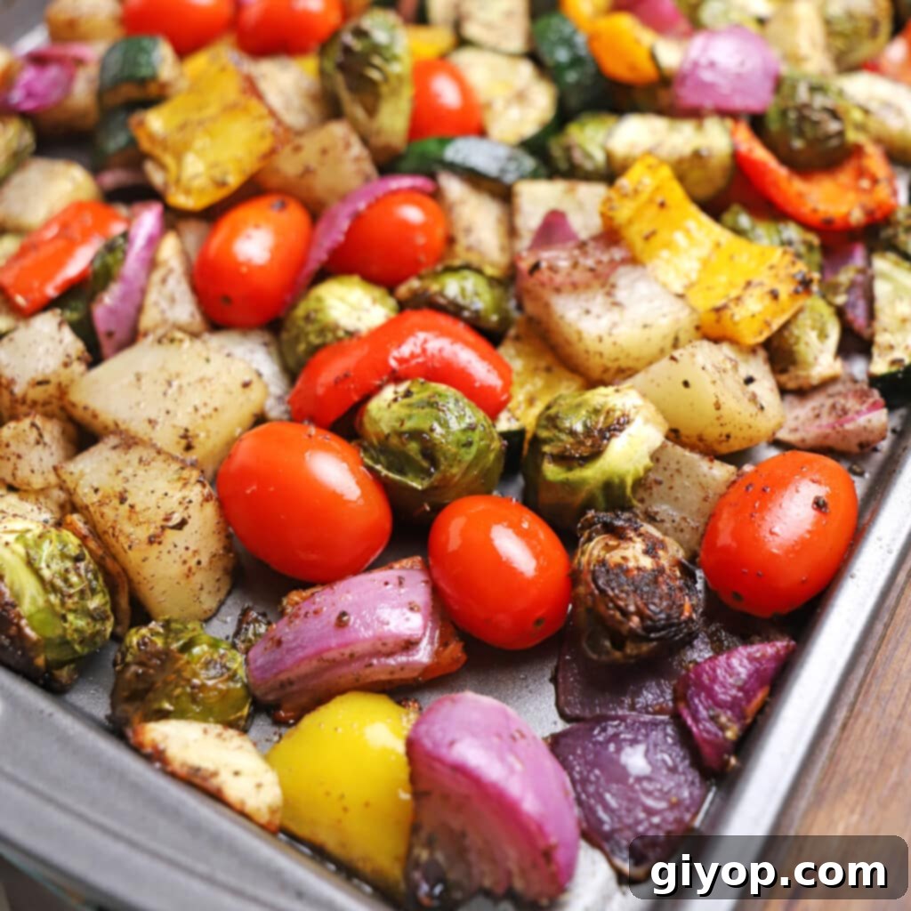 A colorful array of roasted vegetables beautifully arranged on a baking sheet, featuring vibrant greens, reds, and yellows.