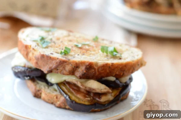 Close-up of an eggplant and cheese sandwich on a plate, highlighting the melted cheese.