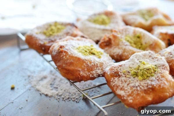 A close up of freshly fried Nabulsi Tamriyeh, dusted with powdered sugar, arranged on a serving tray.