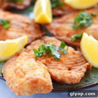 Crispy golden pan-fried tilapia fillets garnished with lemon wedges and fresh parsley.