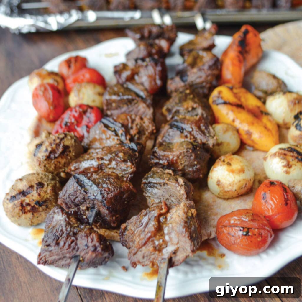Succulent shish kabob skewers with marinated beef and colorful vegetables, beautifully arranged on a white plate.