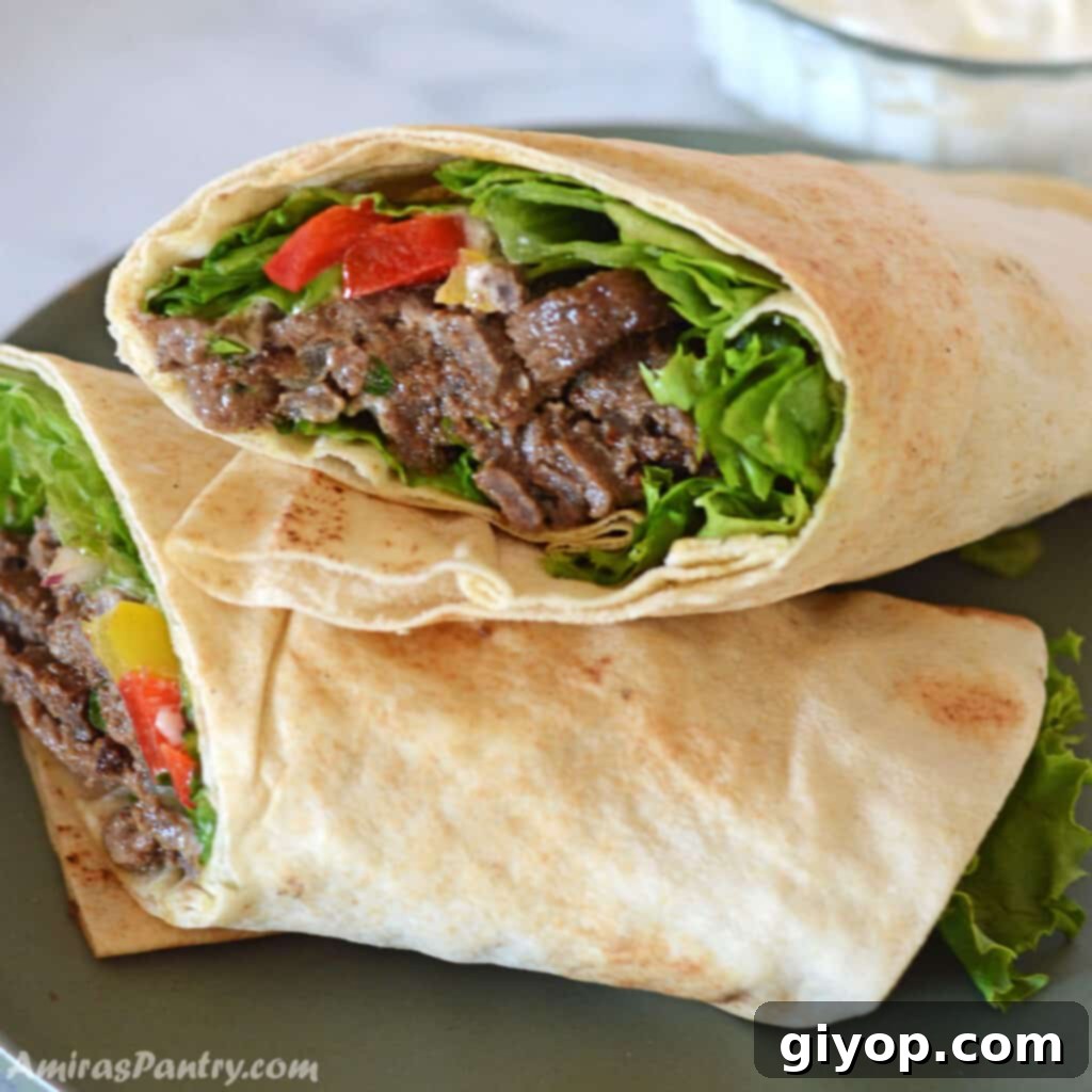 Two halves of perfectly grilled beef shawarma wraps, generously filled and stacked on a vibrant green plate.