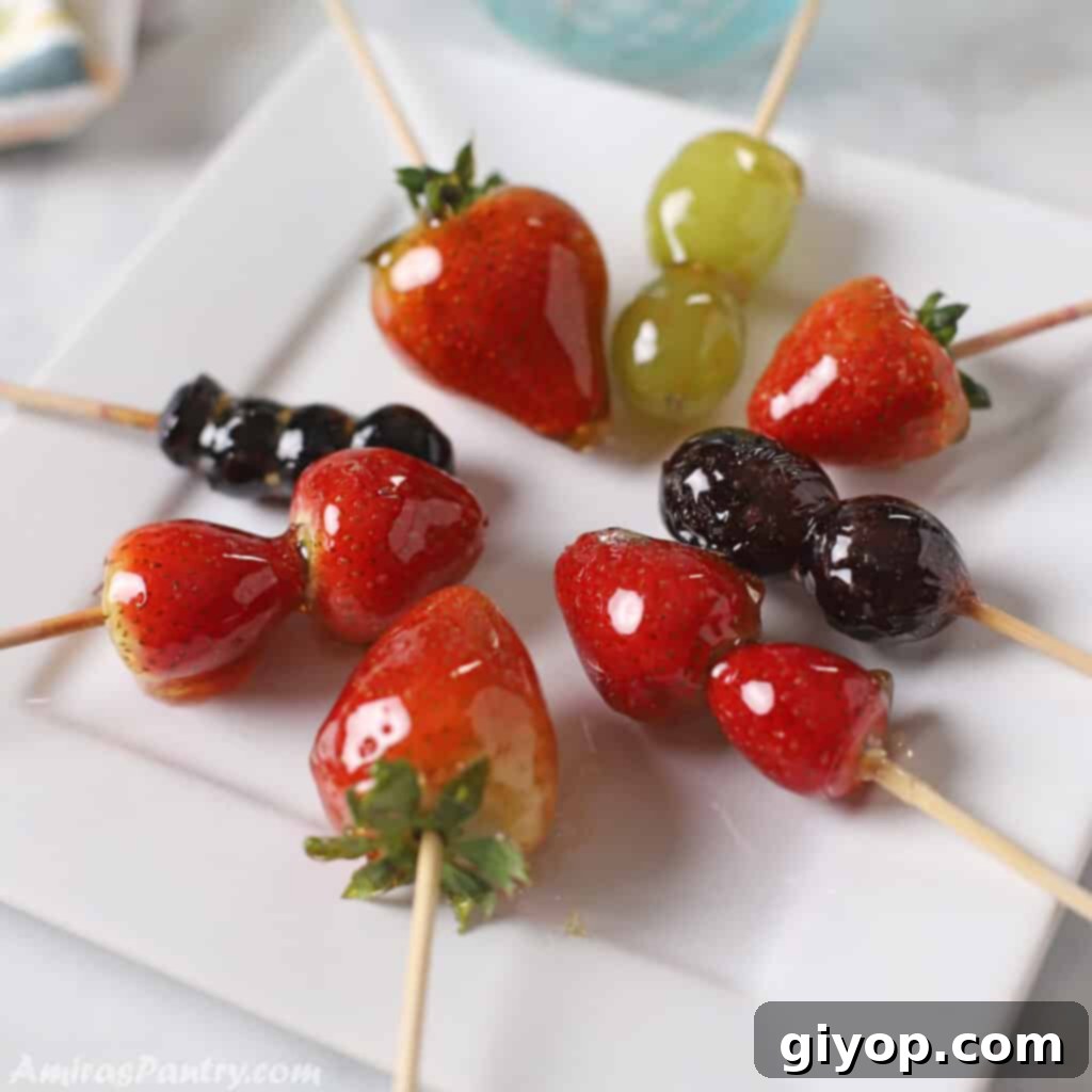 Vibrant Tanghulu skewers featuring glossy strawberries, grapes, and blueberries on a white plate, showcasing their crystalized sugar coating.