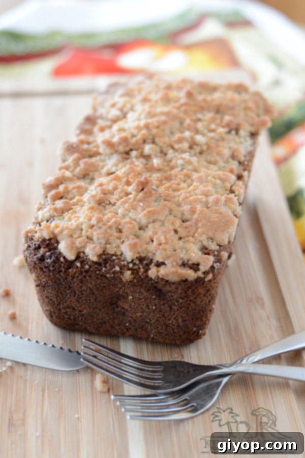 Cozy Apple Cinnamon Crumb Bread 6 A piece of apple bread on a wooden board with a fork