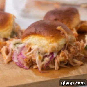 A close up image of a chicken slider on a wooden cutting board, showcasing its rich filling.