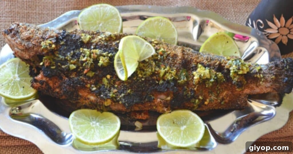 A beautifully grilled trout on a silver serving platter, garnished with fresh lemon rinds, ready to be enjoyed.