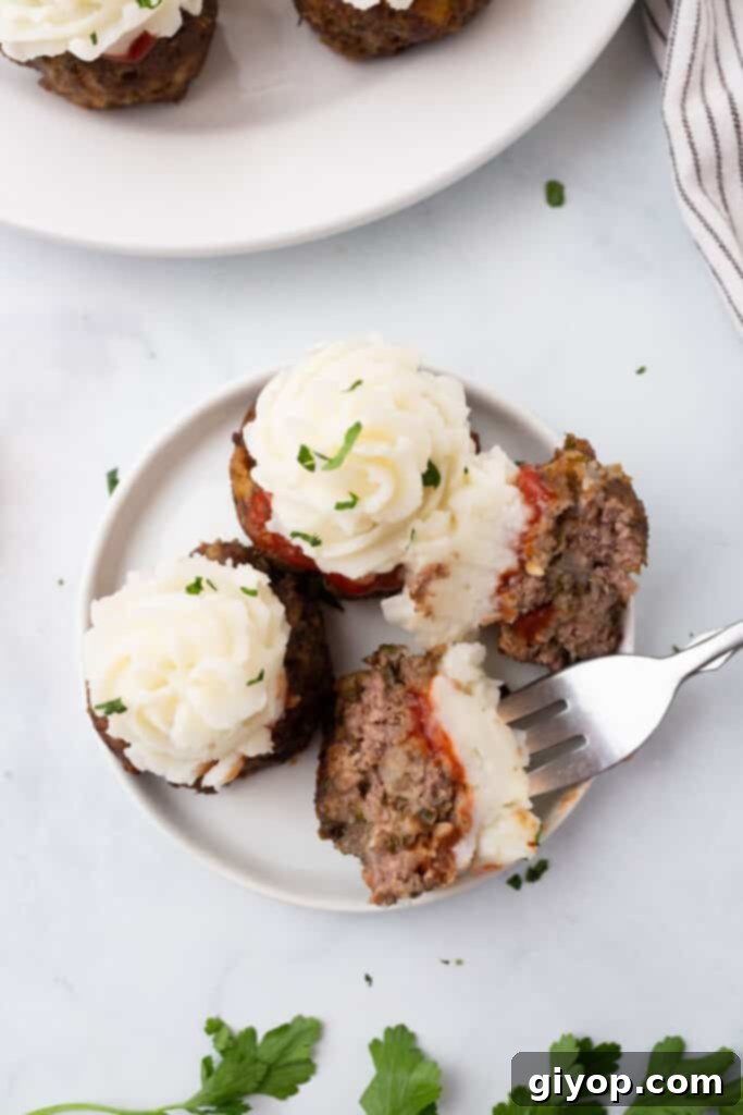 Three perfectly portioned meatloaf cupcakes on a white plate, served with a fork, ready to be enjoyed.