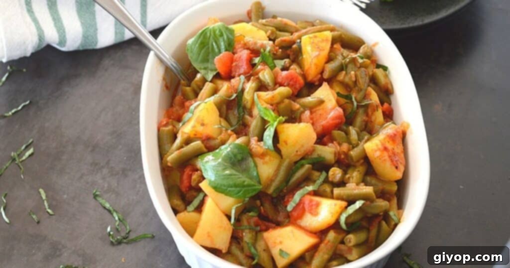 A white casserole dish filled with Greek-style green beans, garnished with fresh basil leaves.