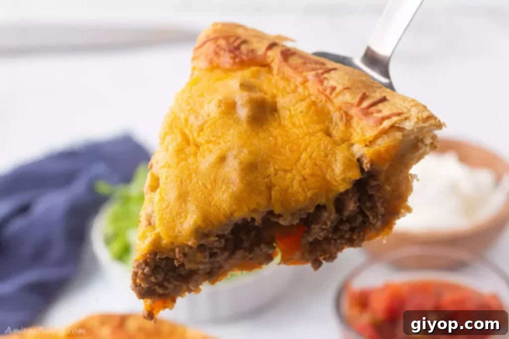 A serving spoon lifting a wedge of golden-brown taco bake from a casserole dish.
