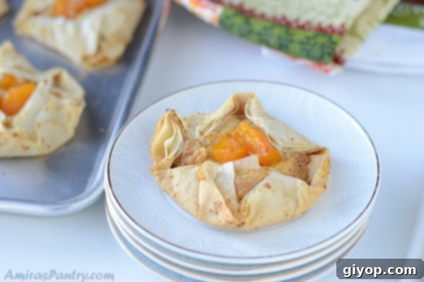 A close-up of an eggless pumpkin frangipane tart on a stack of pristine white plates, with a sheet pan subtly visible in the background, showcasing its flaky texture and rich filling.