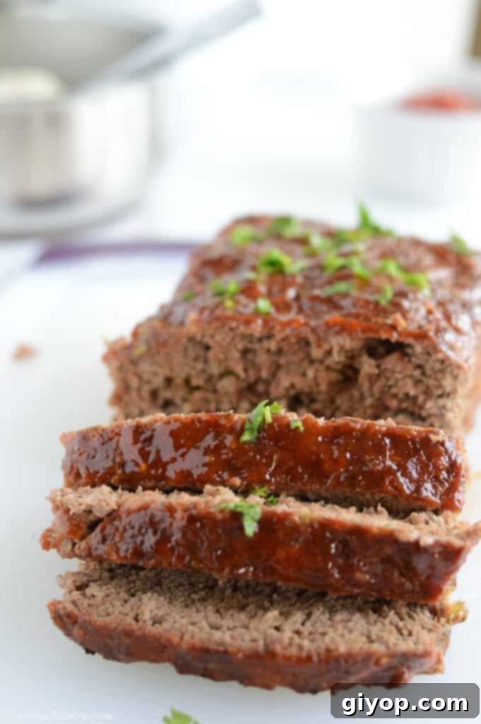Meal Plan 72 3 Perfectly sliced, moist homemade meatloaf on a pristine white plate, showcasing its rich texture and savory glaze.