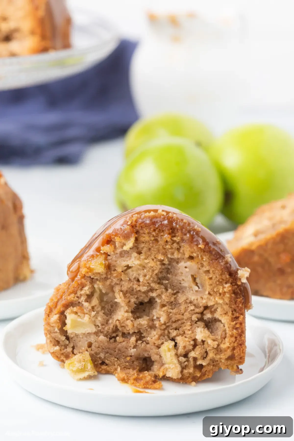 A beautifully sliced caramel apple bundt cake on a white dessert table, showcasing its moist texture and apple chunks.