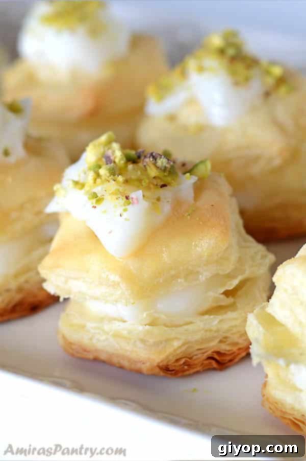 Shaabiyat: The Middle East's Golden Flaky Treat 2 Shaabiyat stuffed and topped with cream and garnished with pistachios on a white plate.