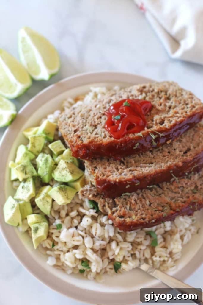 Healthy Meal Plan 5 A plate featuring a generous slice of turkey meatloaf, accompanied by fluffy rice and a dollop of guacamole.