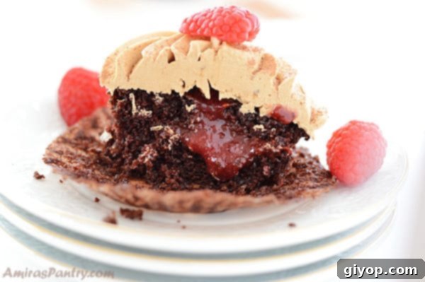 A close-up view of a coffee cupcake cut in half, revealing the vibrant raspberry filling nestled inside.
