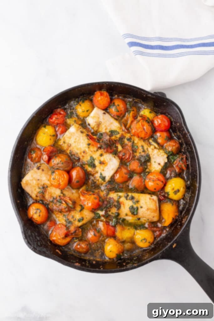 Meal Plan 4 A bird's eye view of a sizzling cast iron skillet, featuring perfectly baked fish fillets adorned with burst grape tomatoes, ready for a healthy meal.