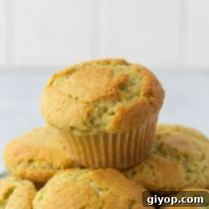 Stack of pistachio muffins on a white plate, showcasing their fluffy texture and inviting green color.