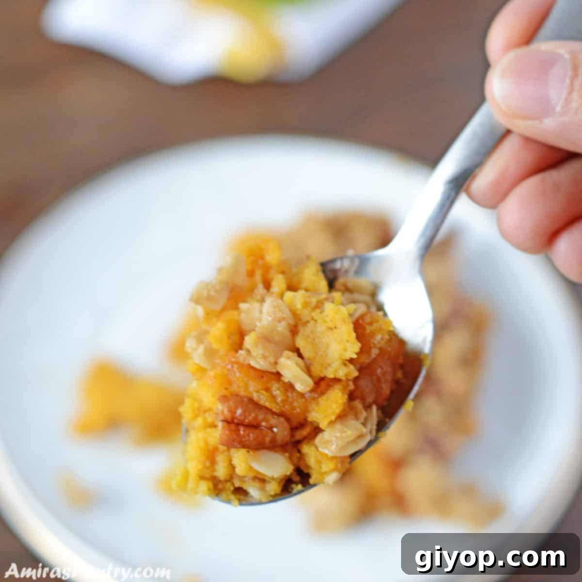 Sweet Golden Butternut Bake 5 A hand holding a spoon scooping some butternut squash with the crunchy topping.