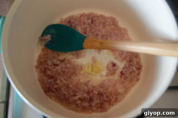 A bowl of food on a stove, with onions and spoon