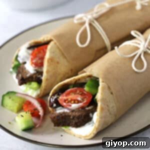 Two gyro wraps on plate with greek salad.