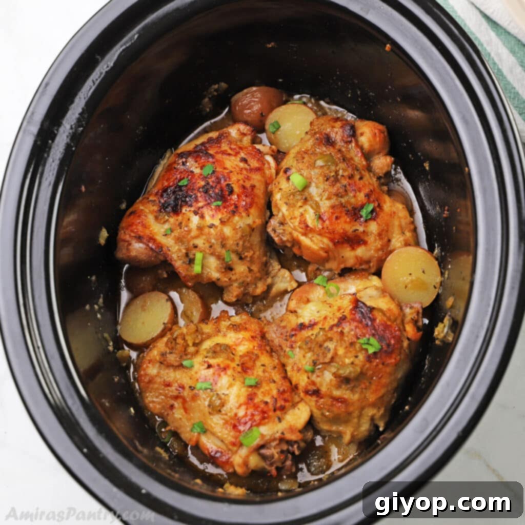 A slow cooker filled with succulent chicken thighs and tender potatoes, infused with incredible flavors, perfect for a cozy dinner.